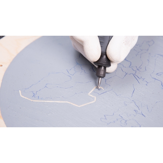 Eine Person, die die nachgezeichnete Zapfenplatte auf Holz graviert, mit einem Dremel-Multitool mit einem 191-Zubehör