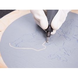 Eine Person, die die nachgezeichnete Zapfenplatte auf Holz graviert, mit einem Dremel-Multitool mit einem 191-Zubehör