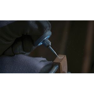 Una persona grabando en una pieza de madera, utilizando una multiherramienta Dremel acoplada a la broca de grabado Dremel 105