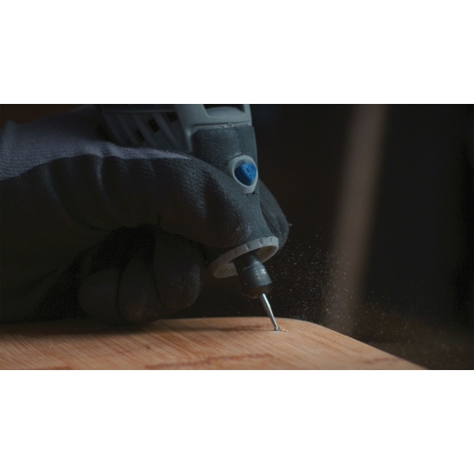 Una multiherramienta Dremel acoplada a la broca de grabado Dremel 107 que se utiliza en una pieza de madera
