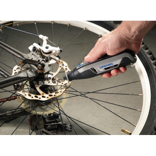 Una persona que usa Dremel 7760 lite para limpiar el óxido de una rueda de bicicleta